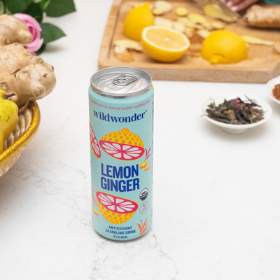 A can of lemon ginger, featuring fresh lemons and ginger being cut in the background.
