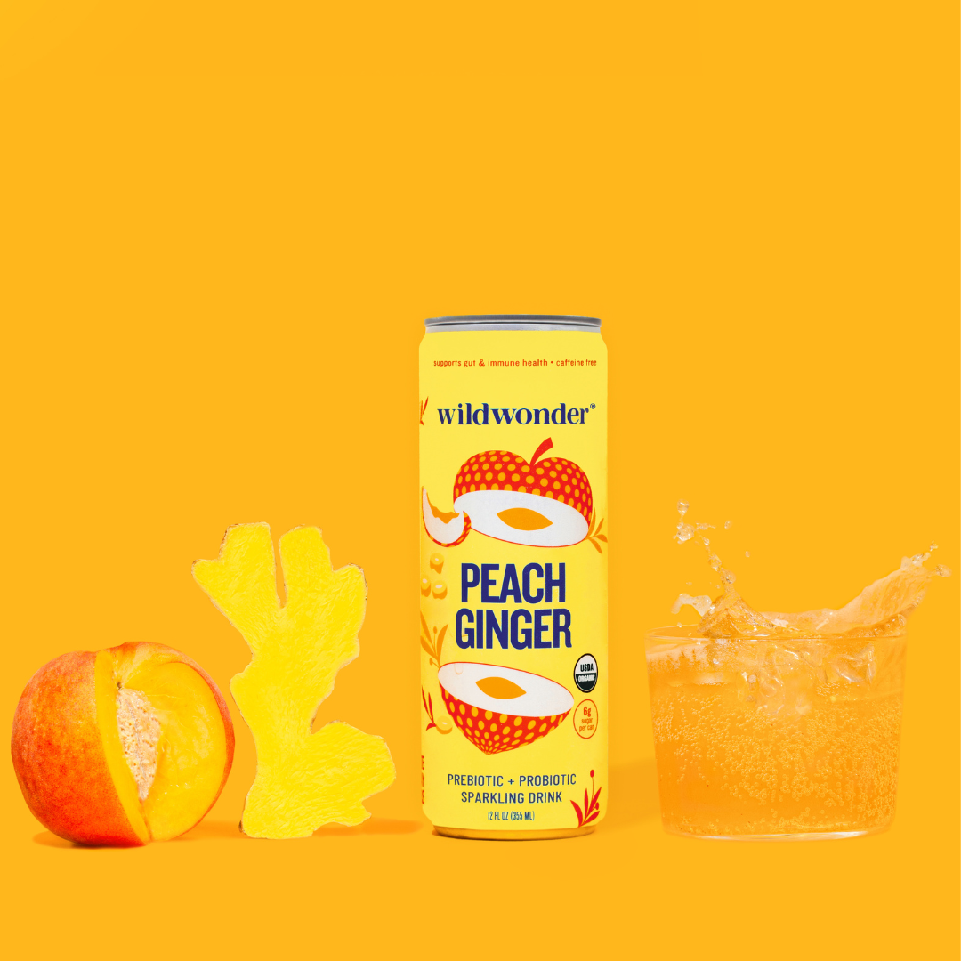 A can of Peach Ginger next to a poured glass, with a fresh peach and ginger root.